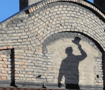Schatten von Rauchfangkehrer am Dach mit Zylinder in der Hand