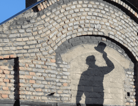 Schatten von Rauchfangkehrer am Dach mit Zylinder in der Hand