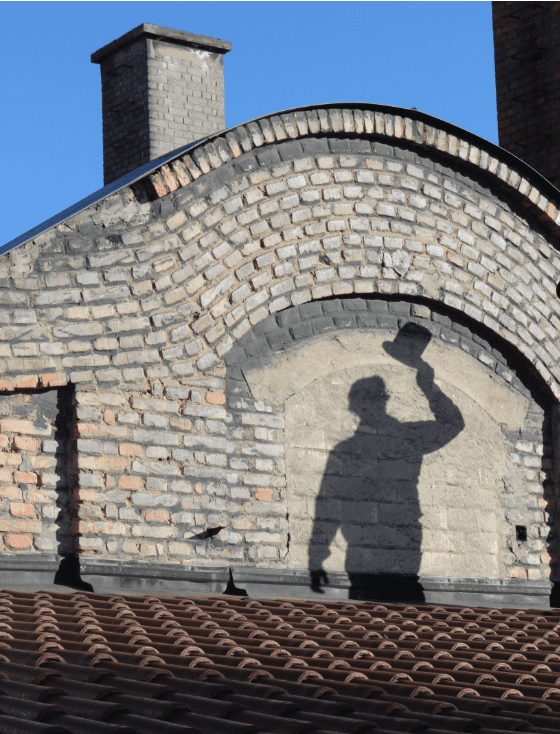 Schatten von Rauchfangkehrer am Dach mit Zylinder in der Hand